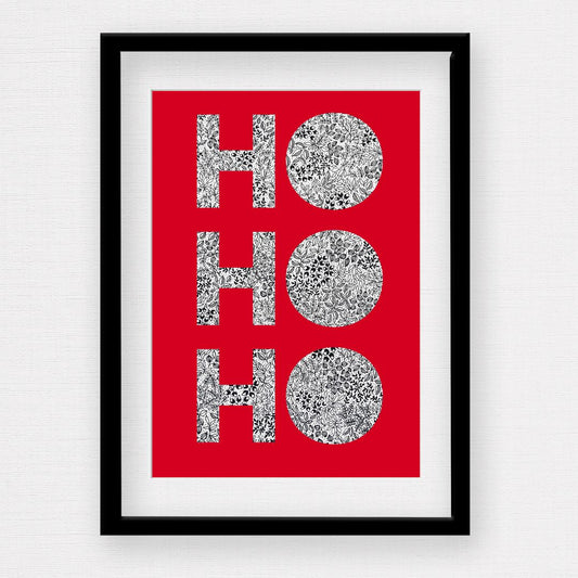 Image shows an original Christmas illustration of the words Ho Ho Ho. The lettering in the words are black and white leaves, petals, and dots. The words are set on a rich red background. For demonstration, the illustration print is set in a black picture frame with a white mount. The frame is laid out a plain white background.