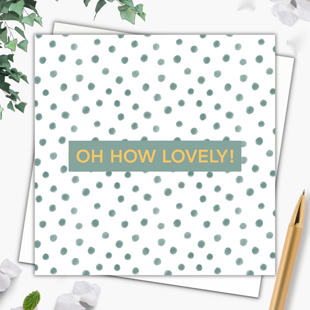 A very pretty celebration card with the words "Oh How Lovely!" in a gold font on a small dark green background. Behind it, the rest of the card is made up of sage green polka dots, giving a natural confetti feeling. The card is lying on a plain white envelope and beside it is a gold pen.