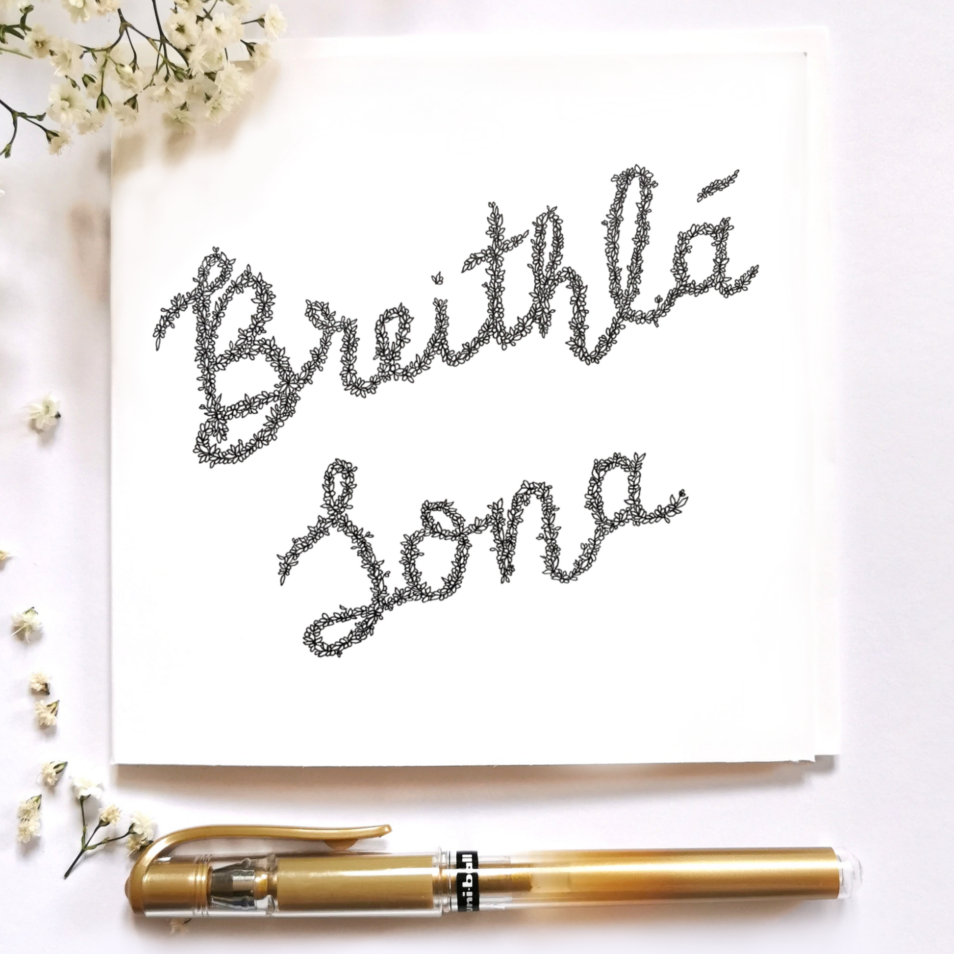 Image shows illustration of an Irish saying ' Breith Lá Sona' meaning Happy Birthday. Illustrations is drawn in joint writing and made entirely of black and white flowers. Image is dressed up with a gold pen and white floral arrangement surrounding the illustraton to display what image could look like in portrait.