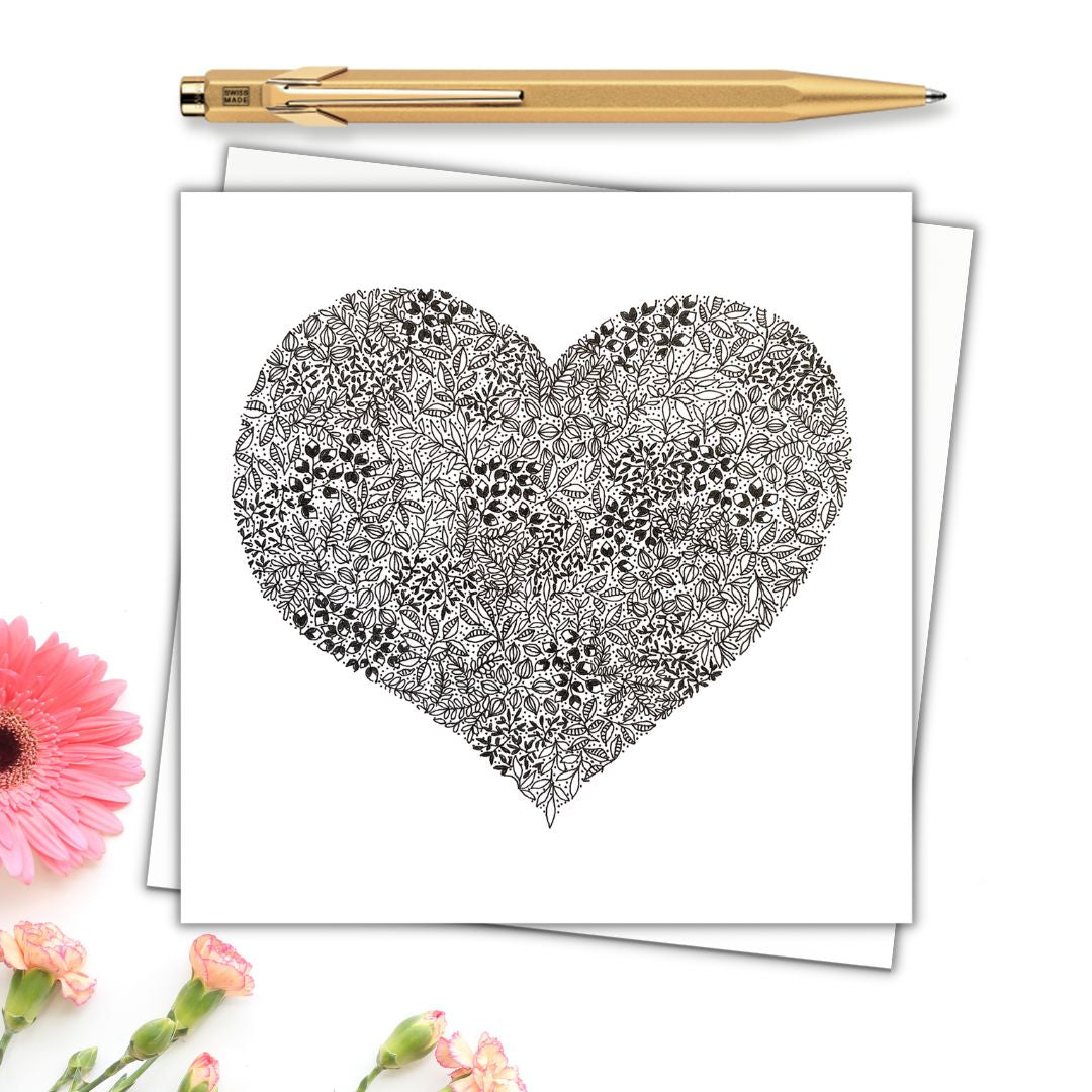 Illustration shows a large heart centred on the page. The heart is made from Black and white floral drawings and there's a gold pen at the top of the image with some pink flowers at the bottom to show what it would look like dressed up. 