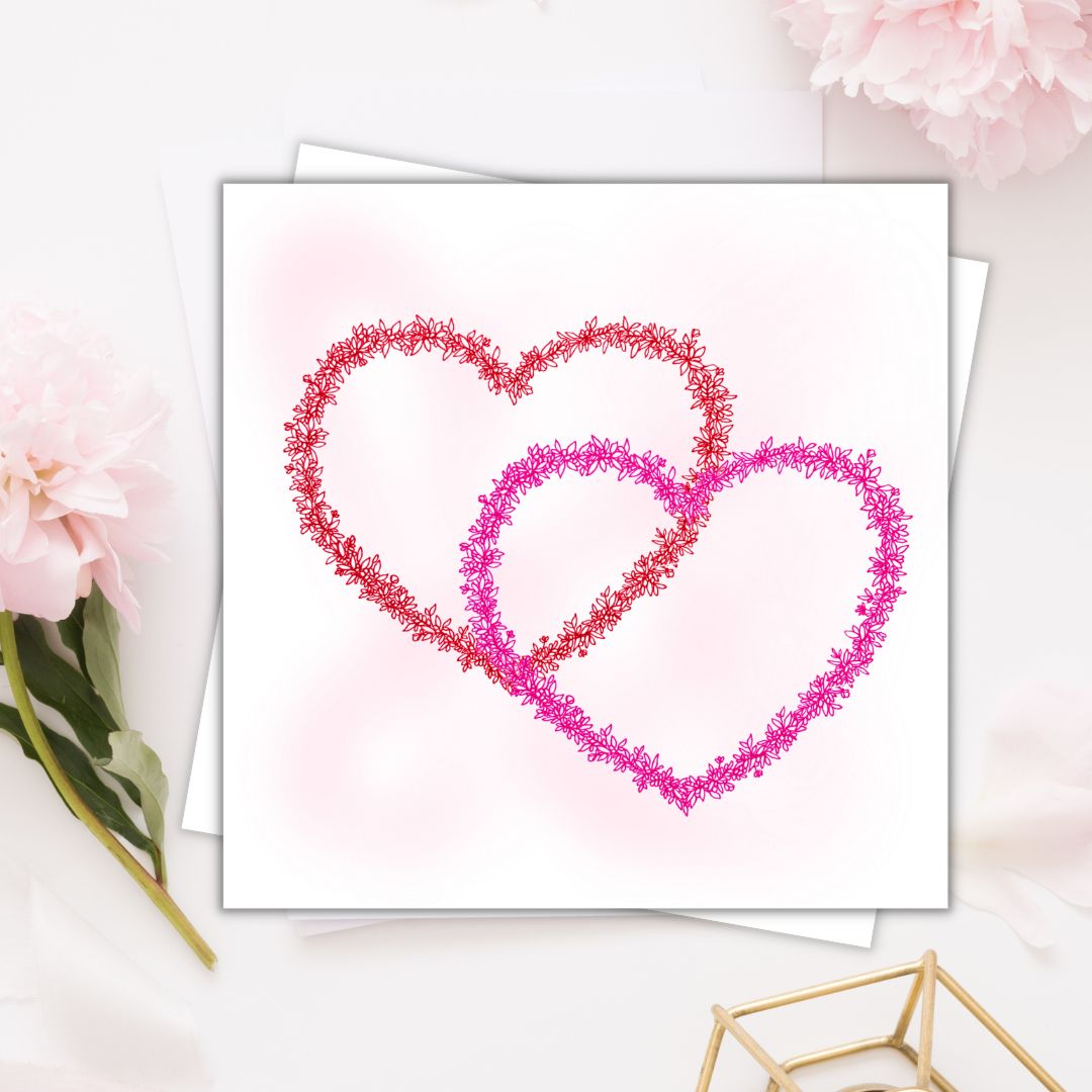 Image shows two hearts ( red & pink) illustration made from floral drawings. hearts meet ways. Image laid on cream surface with white floral arrangements. 